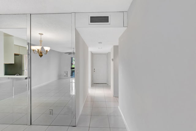 corridor with light tile patterned floors, a chandelier, and baseboards