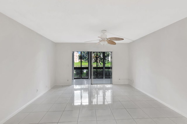 empty room with ceiling fan, light tile patterned flooring, and baseboards