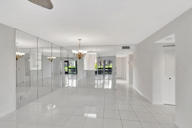 spare room with tile patterned floors, visible vents, baseboards, and an inviting chandelier