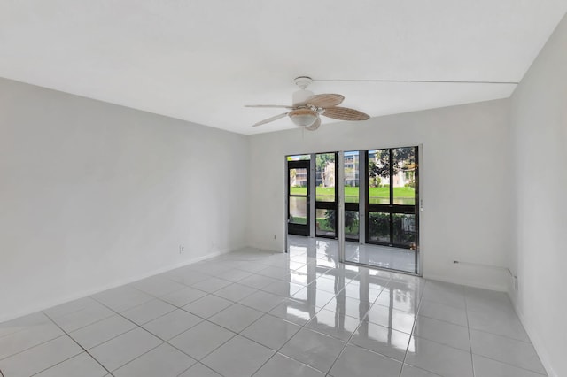 empty room with light tile patterned floors, baseboards, and a ceiling fan