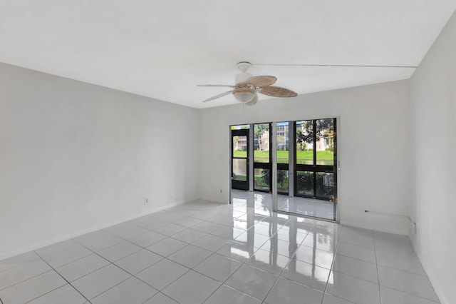 empty room with light tile patterned floors, a ceiling fan, and baseboards