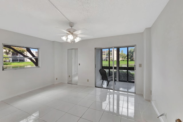 empty room featuring light tile patterned floors, ceiling fan, and baseboards