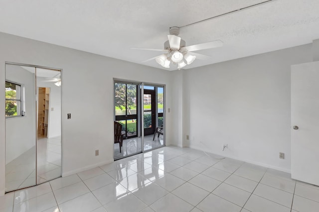 spare room featuring a ceiling fan, light tile patterned floors, and baseboards