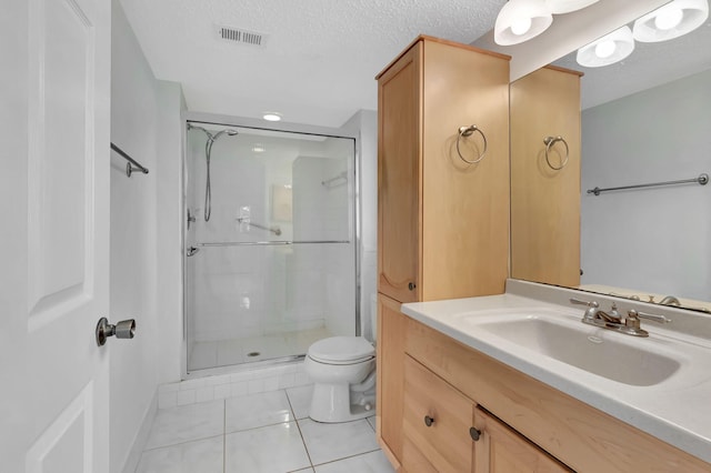 full bathroom featuring a shower stall, toilet, vanity, tile patterned floors, and a textured ceiling