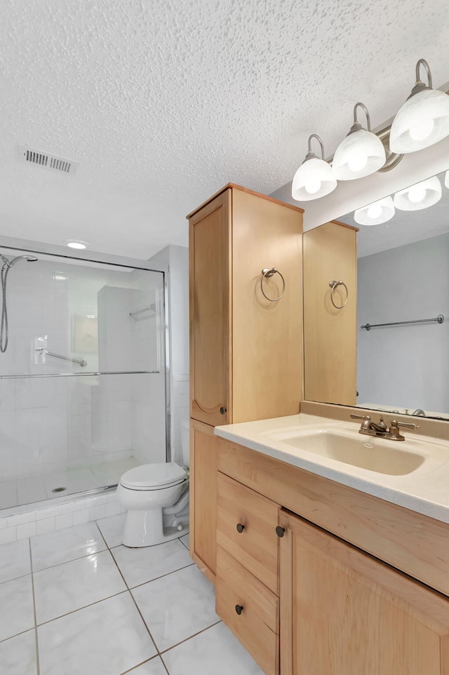 bathroom with a shower stall, vanity, toilet, a textured ceiling, and tile patterned flooring