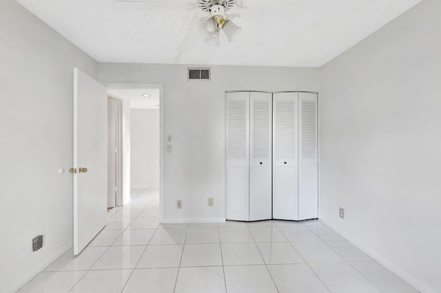 unfurnished bedroom with light tile patterned floors, baseboards, visible vents, a ceiling fan, and a closet