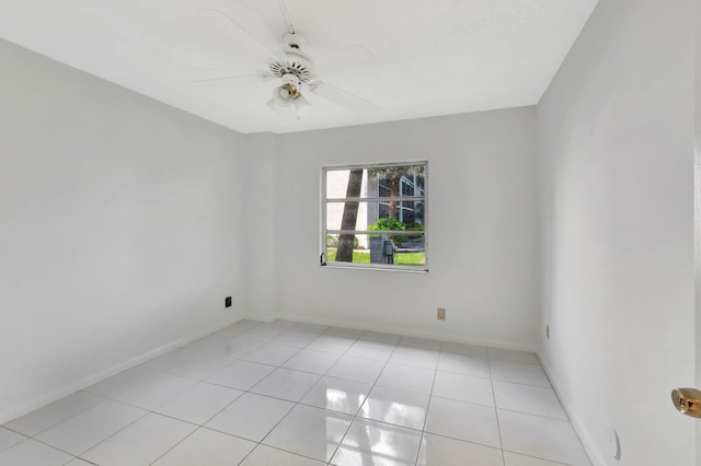 empty room featuring a ceiling fan, light tile patterned flooring, and baseboards