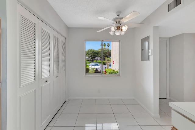 unfurnished bedroom featuring light tile patterned flooring, baseboards, electric panel, and ceiling fan