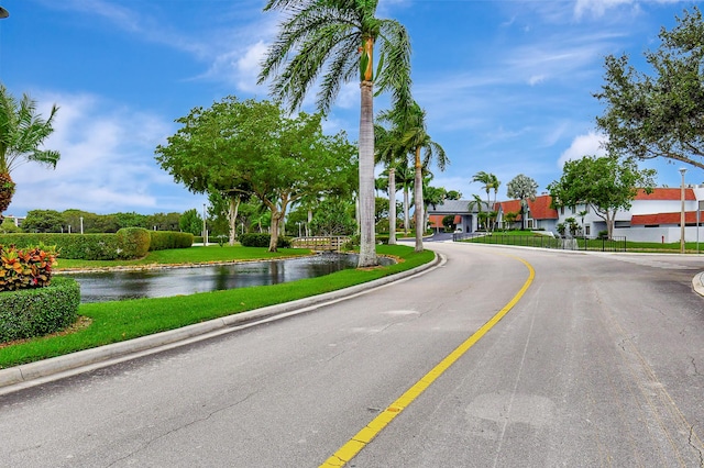view of asphalt road featuring a water view and curbs