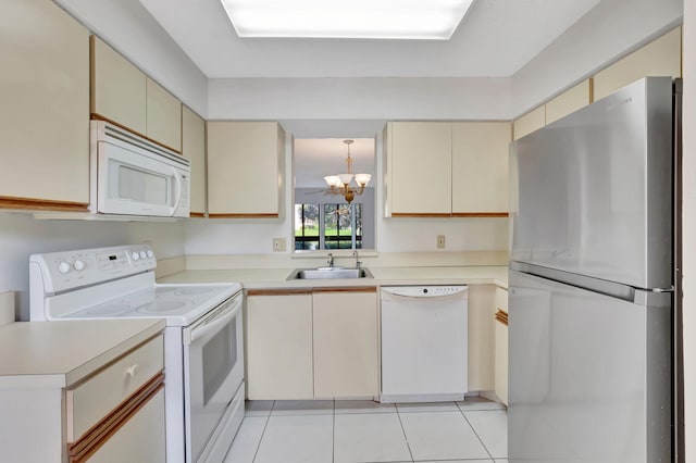 kitchen with white appliances, cream cabinets, light countertops, and a sink