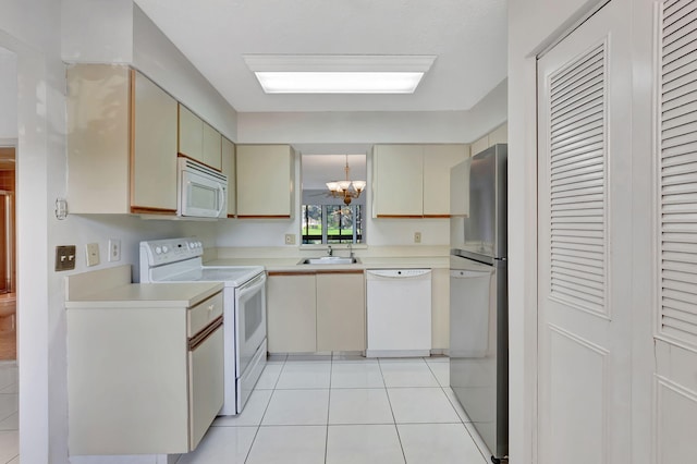 kitchen with white appliances, light countertops, cream cabinetry, light tile patterned floors, and a chandelier