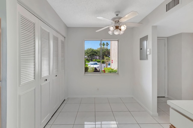 interior space with light tile patterned floors, electric panel, baseboards, visible vents, and a textured ceiling