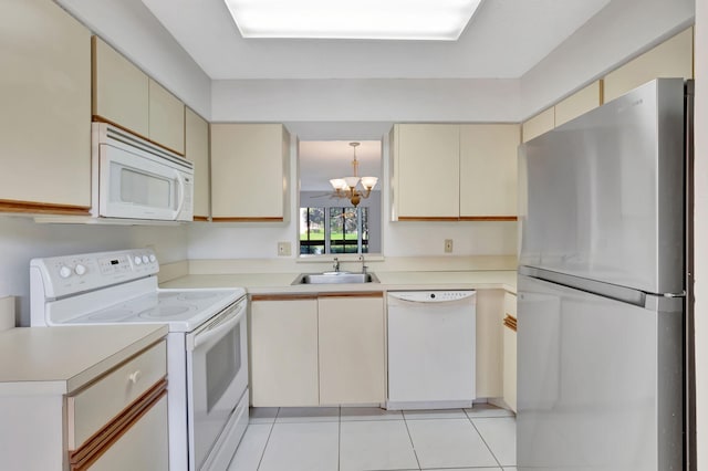 kitchen featuring white appliances, cream cabinetry, a chandelier, and light countertops