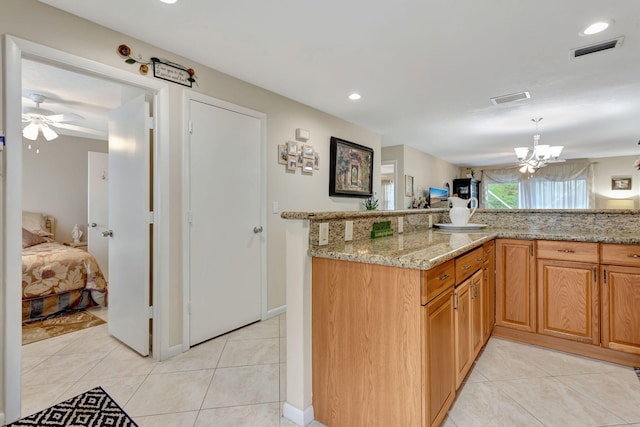 kitchen with visible vents, pendant lighting, light stone counters, and light tile patterned flooring