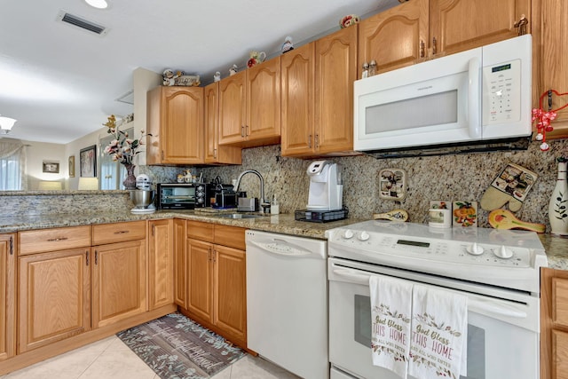 kitchen with light tile patterned floors, white appliances, a sink, visible vents, and backsplash