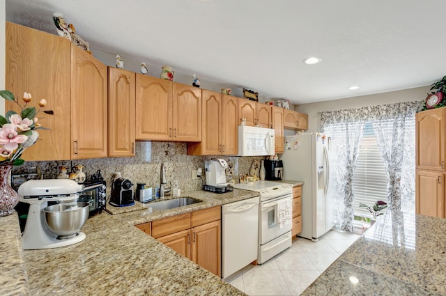 kitchen with light tile patterned floors, light stone counters, white appliances, a sink, and backsplash