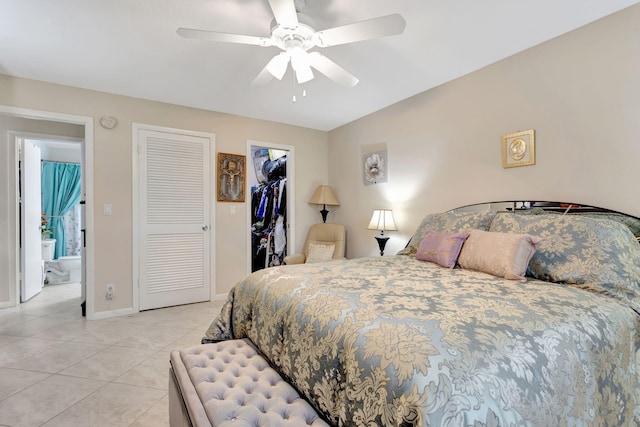 bedroom with baseboards, a ceiling fan, a walk in closet, a closet, and light tile patterned flooring