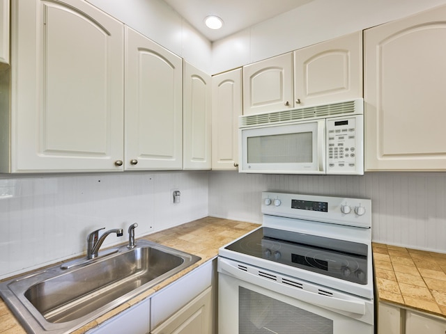 kitchen with white appliances, light countertops, a sink, and white cabinets