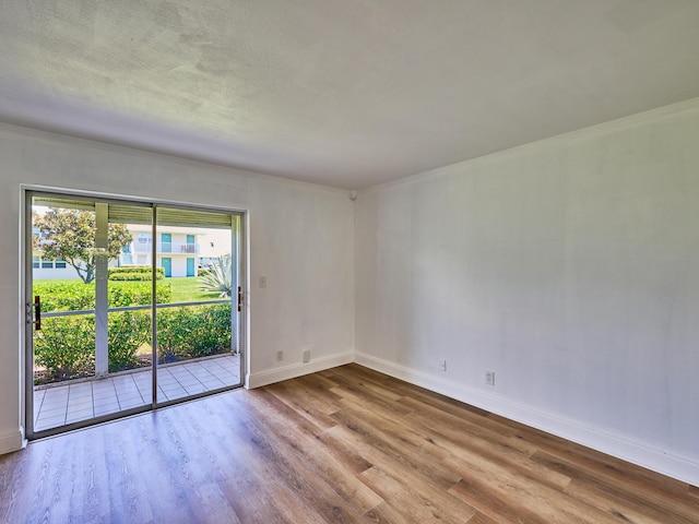 empty room with a textured ceiling, wood finished floors, and baseboards