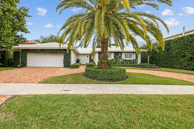 view of front of home with a front yard, decorative driveway, and a garage