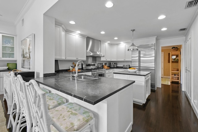 kitchen featuring visible vents, ornamental molding, a sink, appliances with stainless steel finishes, and wall chimney exhaust hood