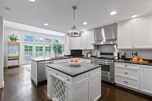 kitchen with a sink, a center island, stainless steel appliances, a peninsula, and wall chimney range hood