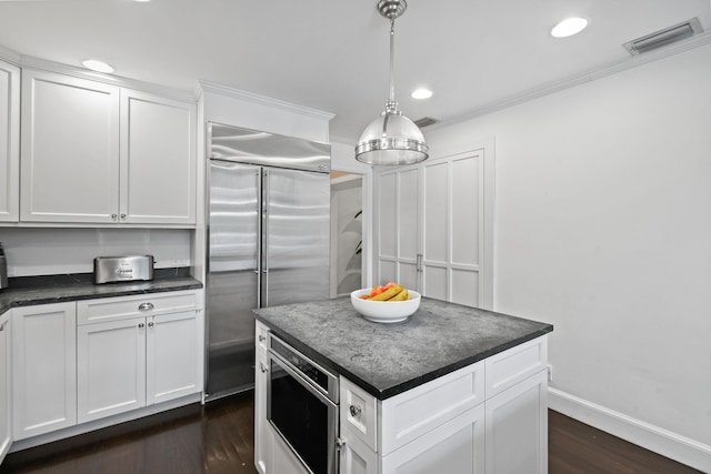 kitchen featuring visible vents, built in refrigerator, dark wood-type flooring, dark countertops, and white cabinets