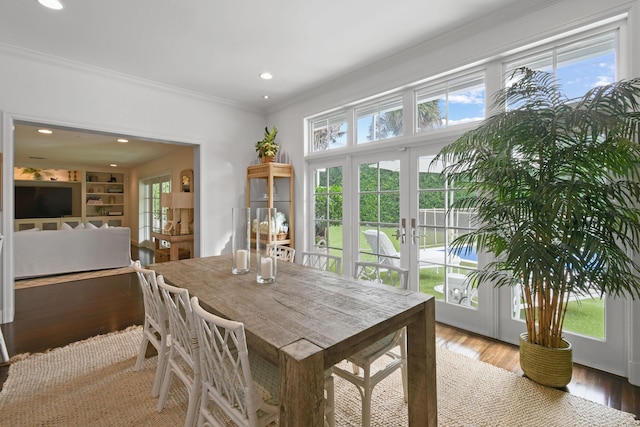 dining area with a wealth of natural light, french doors, crown molding, and wood finished floors