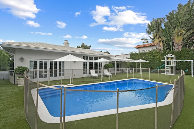 view of swimming pool with a lawn, french doors, and a fenced in pool