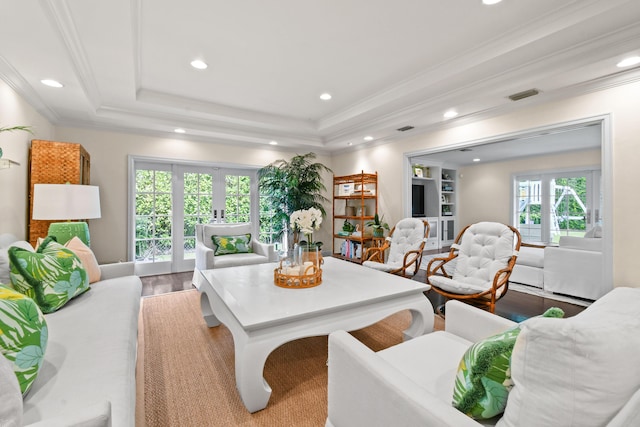 living room with wood finished floors, visible vents, a tray ceiling, recessed lighting, and crown molding