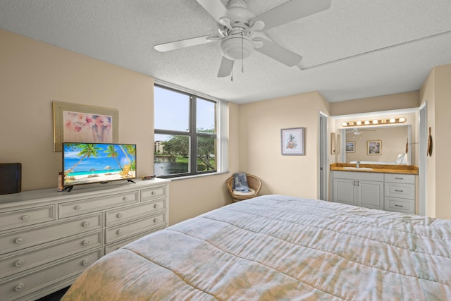 bedroom featuring a sink, connected bathroom, a ceiling fan, and a textured ceiling