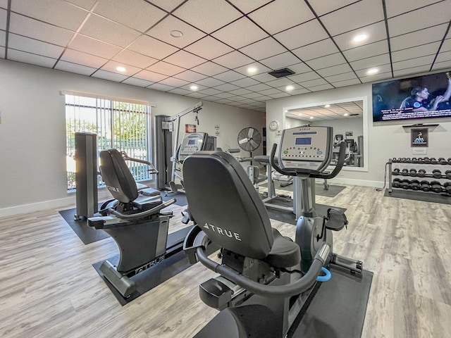 gym featuring a paneled ceiling, baseboards, visible vents, and wood finished floors