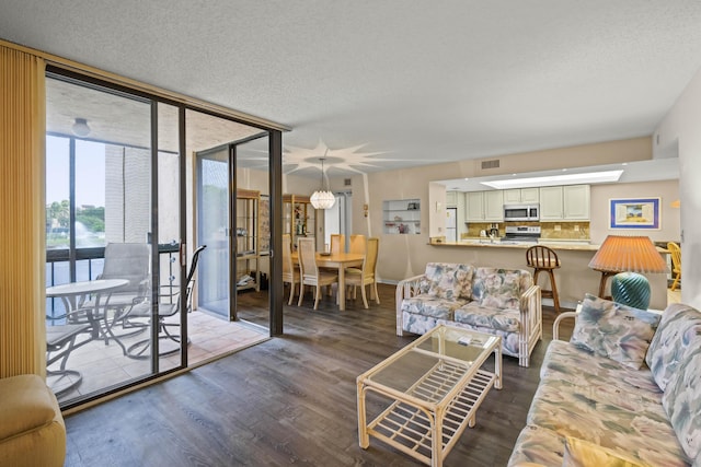 living area featuring a textured ceiling, a wall of windows, wood finished floors, and visible vents