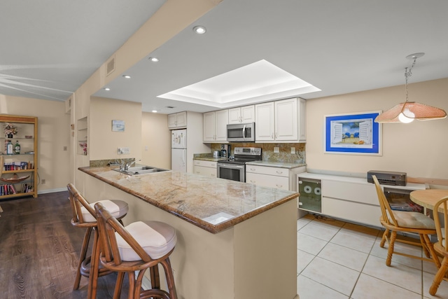 kitchen with stainless steel appliances, visible vents, a sink, a peninsula, and a kitchen bar