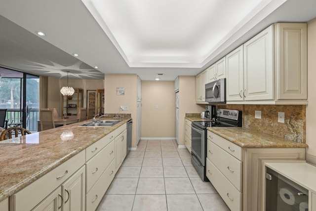 kitchen with light tile patterned floors, decorative backsplash, a tray ceiling, stainless steel appliances, and a sink