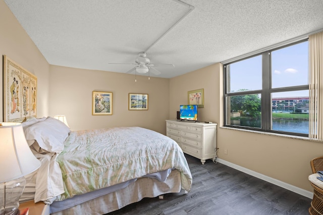 bedroom featuring dark wood-style floors, ceiling fan, a textured ceiling, and baseboards