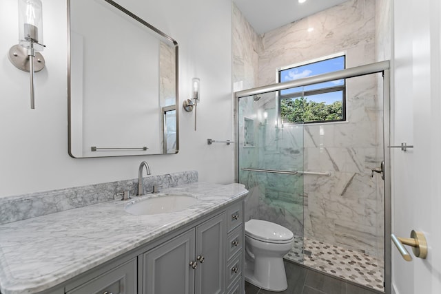 full bathroom with vanity, a marble finish shower, and toilet