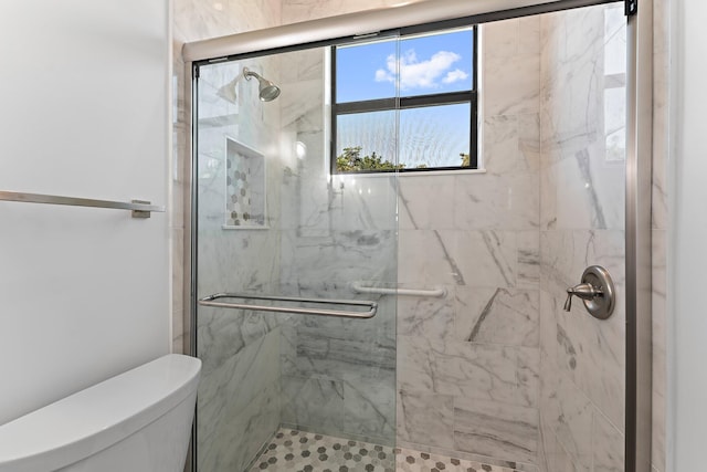 bathroom featuring toilet and a marble finish shower