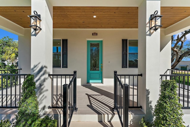 property entrance with covered porch and stucco siding