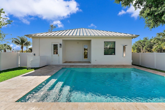 back of house featuring a standing seam roof, fence private yard, and stucco siding