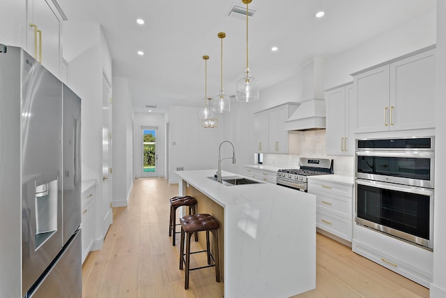 kitchen with visible vents, appliances with stainless steel finishes, a sink, custom exhaust hood, and backsplash