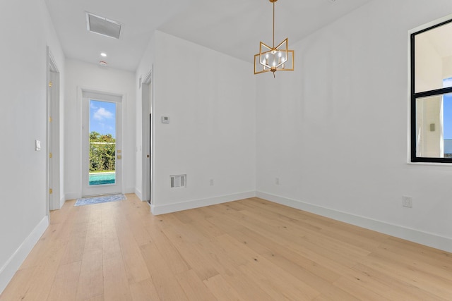 entryway featuring an inviting chandelier, light wood-style flooring, visible vents, and baseboards