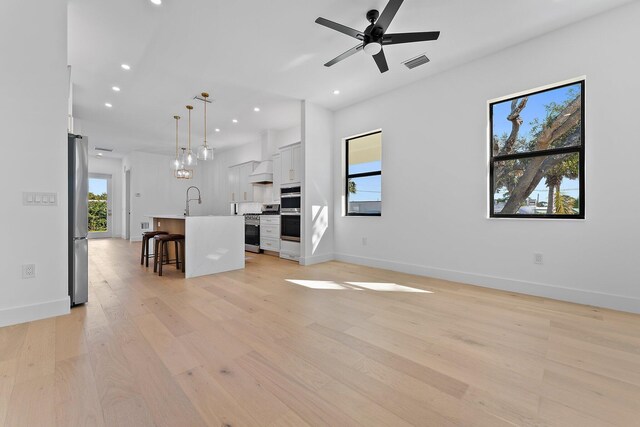 unfurnished living room with light wood-style floors, visible vents, a sink, and recessed lighting