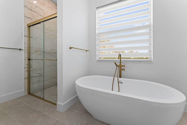 full bathroom with tile patterned flooring, a marble finish shower, baseboards, and a freestanding bath