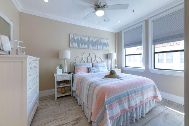 bedroom with ornamental molding, baseboards, light wood finished floors, and a ceiling fan