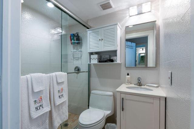 bathroom featuring a stall shower, visible vents, vanity, and toilet