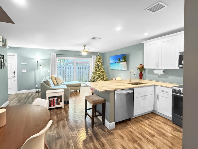 kitchen with visible vents, open floor plan, appliances with stainless steel finishes, a peninsula, and a sink