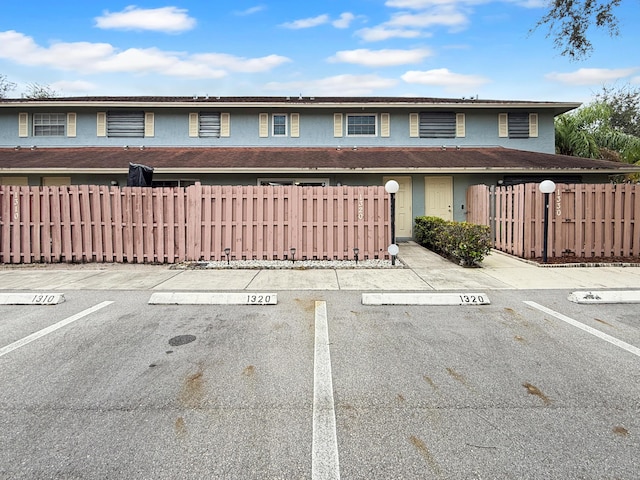 townhome / multi-family property with uncovered parking and fence