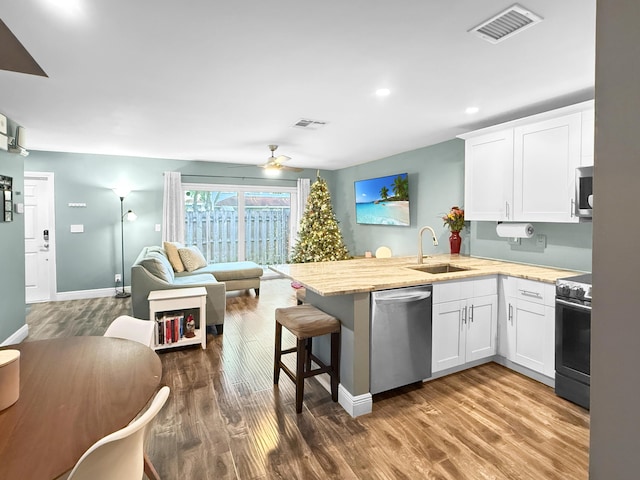 kitchen with visible vents, a peninsula, a sink, appliances with stainless steel finishes, and open floor plan