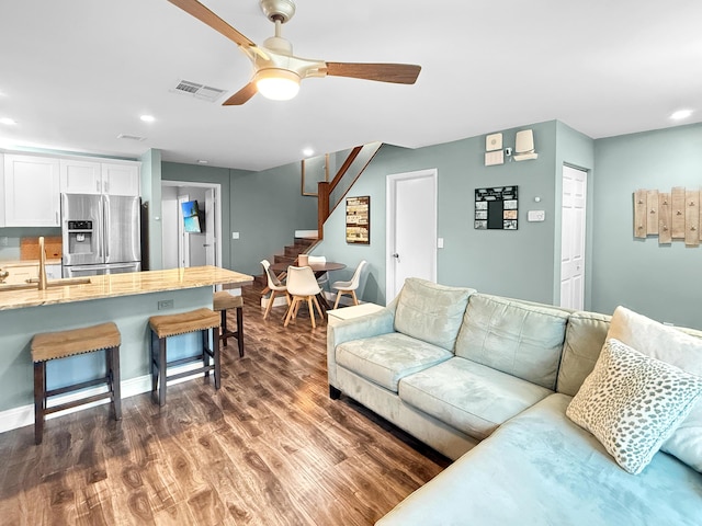 living room with visible vents, baseboards, stairs, dark wood-style floors, and a ceiling fan